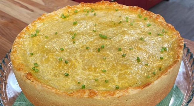 Torta assada inteira com massa de empadão em uma mesa de madeira.