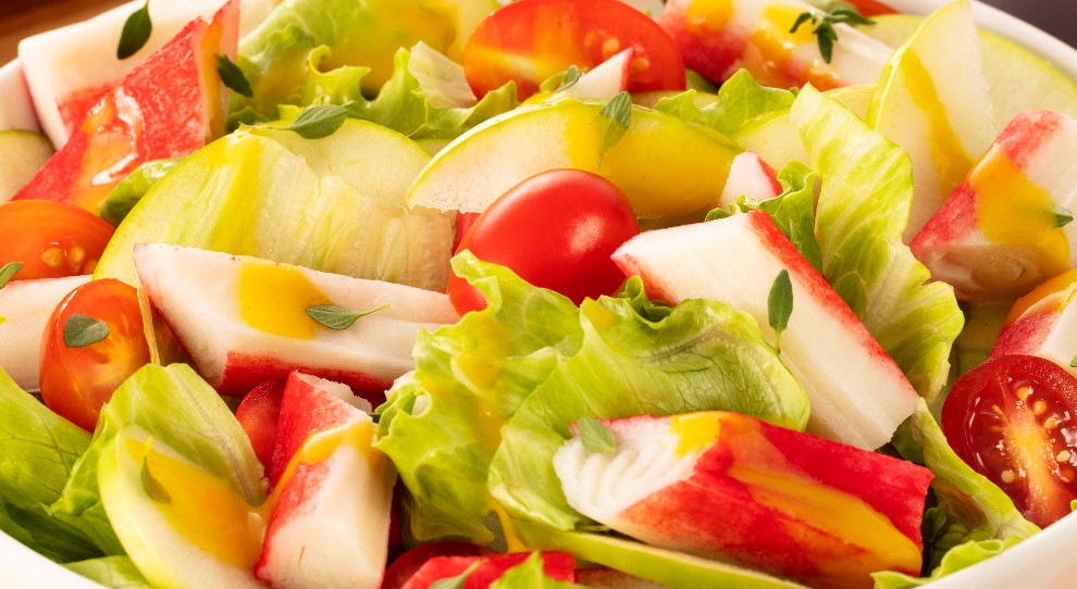 salada de alface com kani e tomate cereja, acompanhada de mostarda.