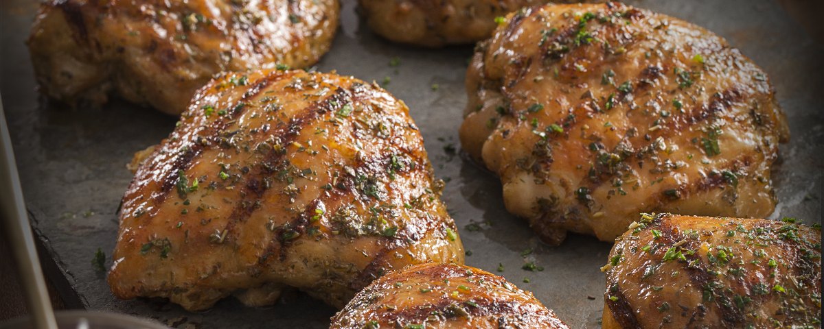 Espetinhos de carne sobre tábua de madeira com farofa de limão e pimenta