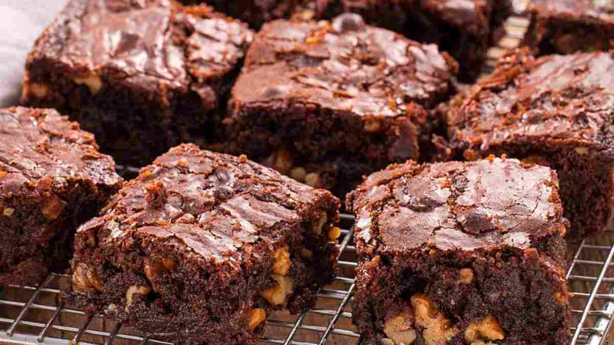 Seis brownies de chocolate recheados com nozes picadas servidos em uma grade de metal.