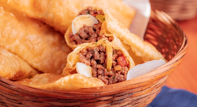 Cesta com pastéis de carne moída em que dois têm o recheio a mostra.