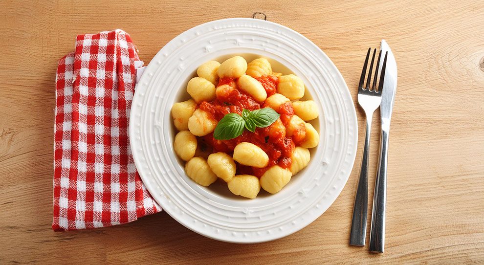 nhoque de batata servido com molho de tomate e com guardanapo xadrez. 