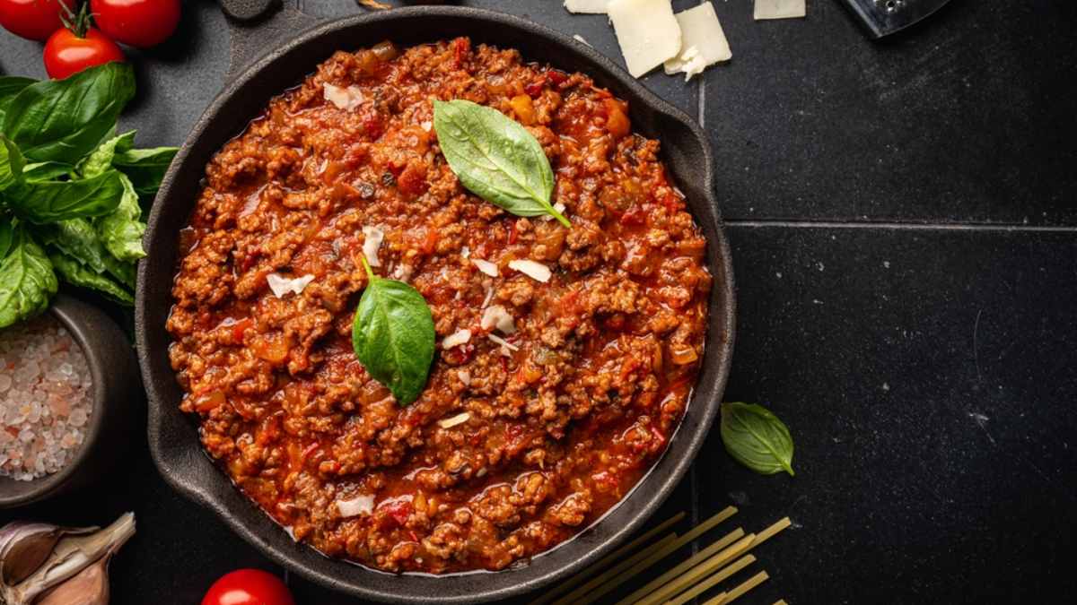 Molho bolonhesa para lasanha de carne moída feito com carne de Acém Reserva Friboi, tomate pelado e manjericão servido em uma panela de ferro preta.