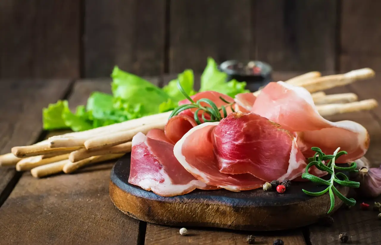 mesa de madeira com grissini e parma ao lado