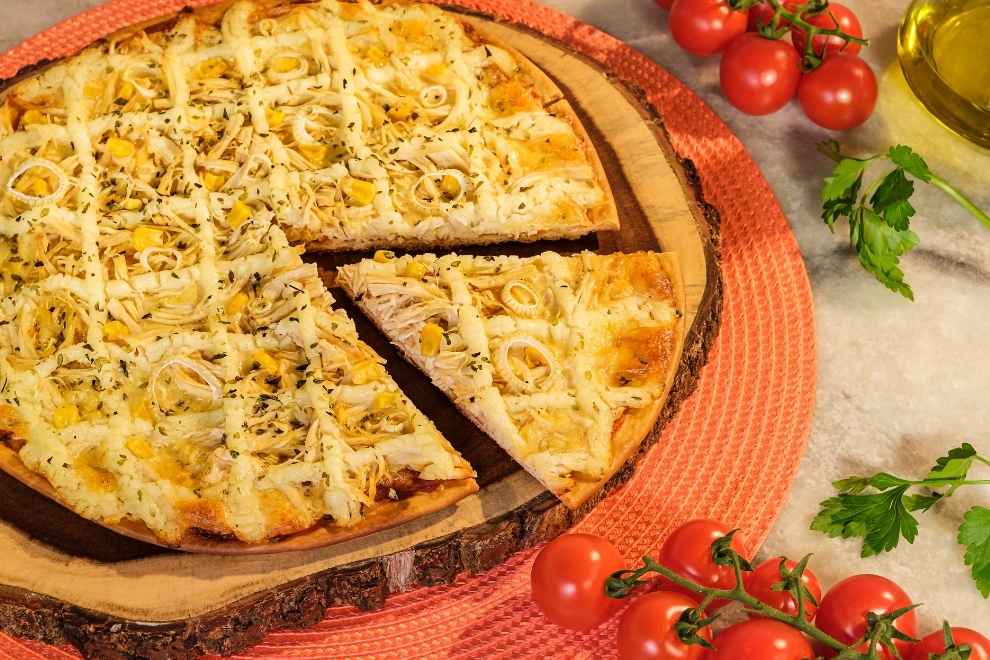 pizza de frango com requeijão com uma fatia cortada