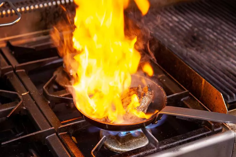 panela em um fogão flambando carne