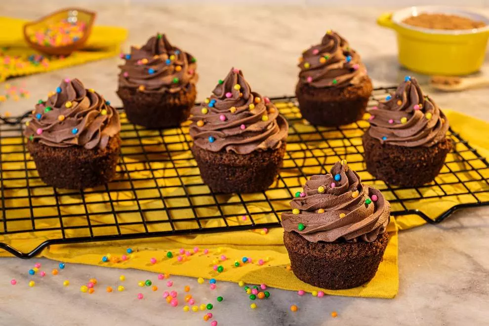 vários cupcake de chocolate em uma mesa branca com toalha amarela 