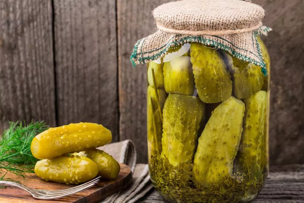 picles em conserva em um pote de vidro em uma mesa de madeira