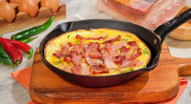 Frittata com legumes servidas com bacon em uma frigideira .