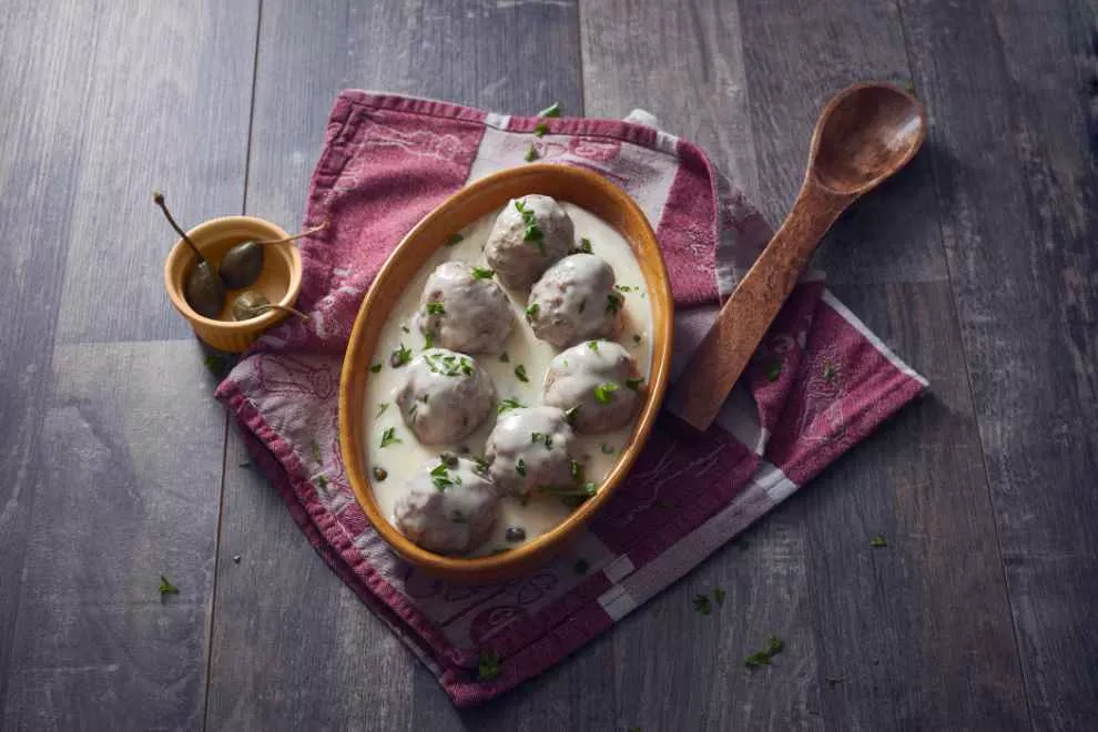 Königsberger Klopse dentro de uma tigela com colher de pão do lado