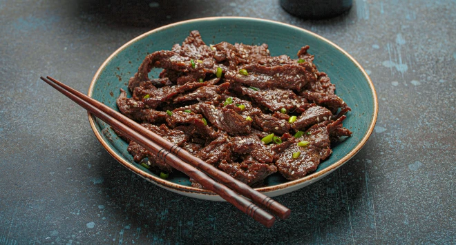 Carne em tiras em uma tigela azul, com um par de hashi por cima