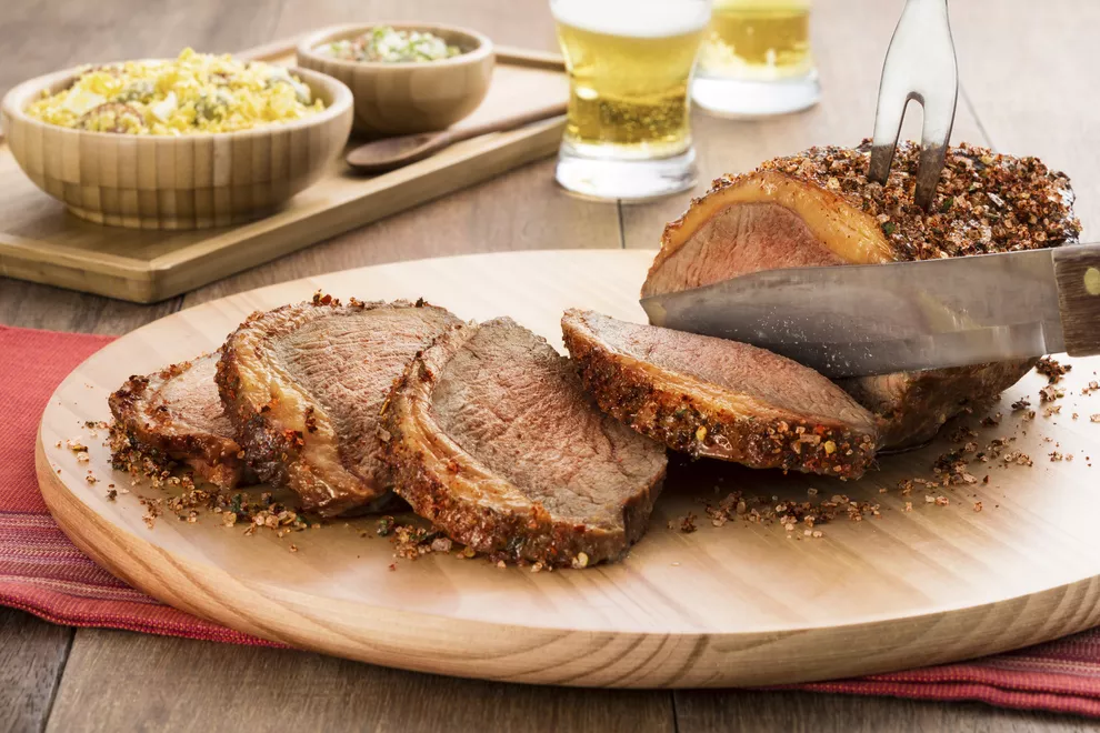 faca de churrasco cortando carne encima de uma tabua de madeira