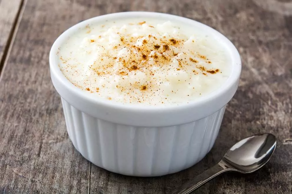 arroz doce com colher ao lado em uma mesa de madeira