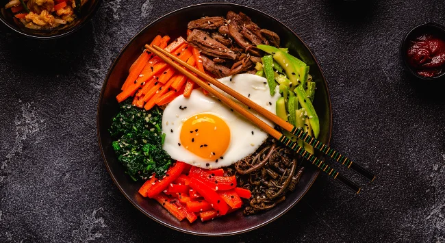 Bibimbap servido em uma tigela preta.