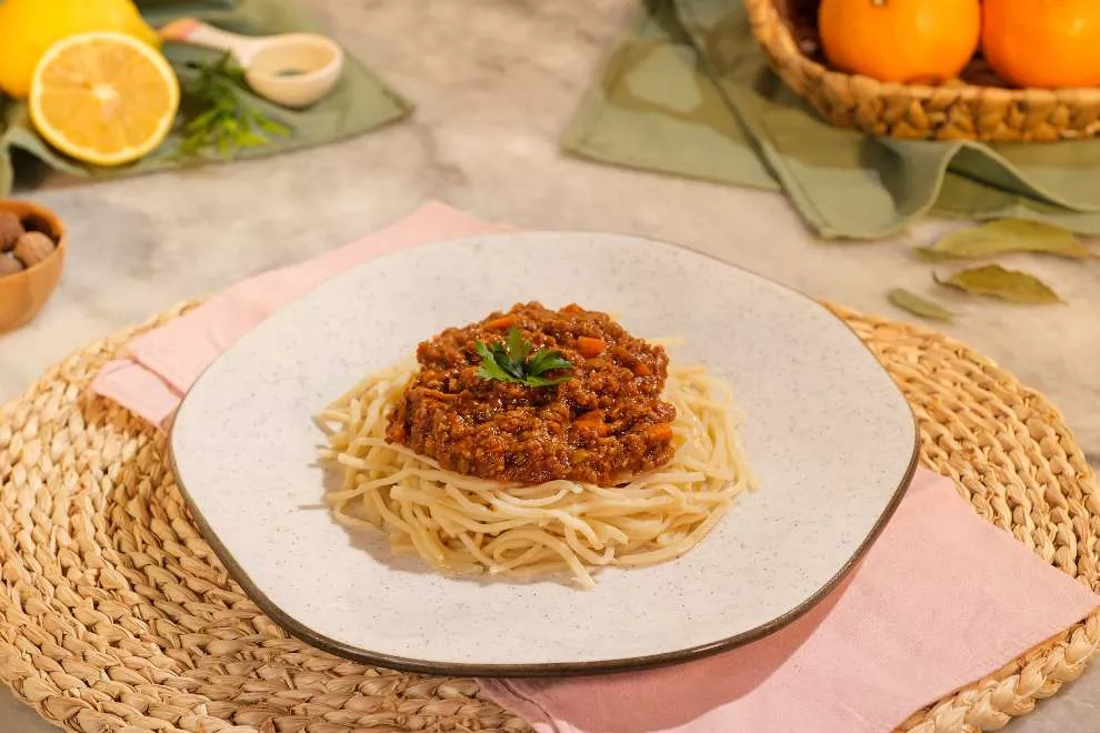 macarrão bolonhesa em um prato encima da mesa de madeira