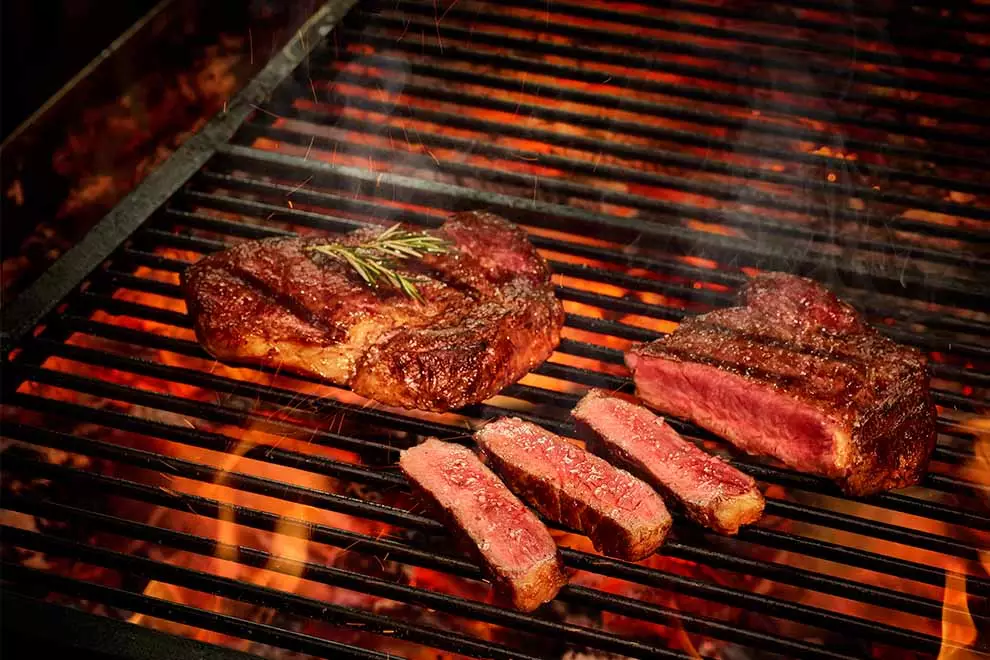 bife ancho grelhado cortado em tiras em cima de uma grelha de churrasco 