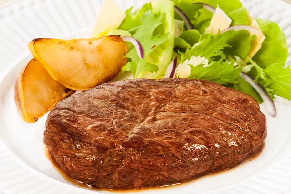 coxão mole com salada de pera dentro de um prato branco de porcelana em cima de uma mesa 