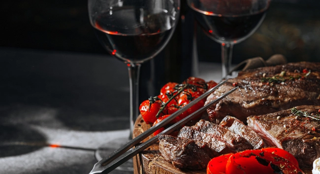 churrasco de carne servido com tomate assado e vinho.