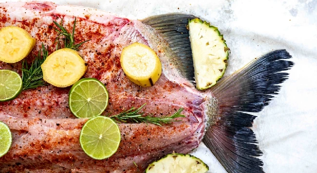 Peixe tambaqui temperado com limões em uma assadeira.